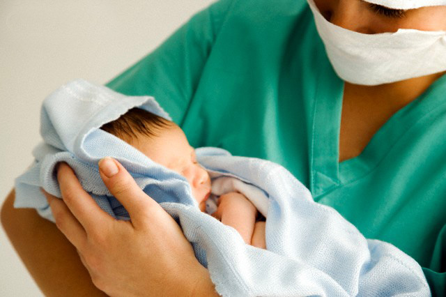 A medical practitioner holding a newborn baby Concorso Ostetriche a Parma, sarà annullato?