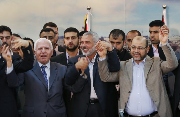 Senior Fatah official Azzam Al-Ahmed, head of the Hamas government Ismail Haniyeh and senior Hamas leader Moussa Abu Marzouq hold their hands after announcing a reconciliation agreement in Gaza City